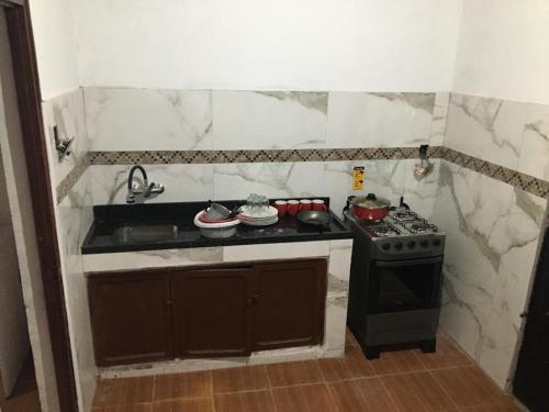 Una pequeña cocina con estufa y fregadero. en N6-CASA CÉNTRICA 2 DORMITORIOS Con AIRE ACONDICIONADO, en Artigas
