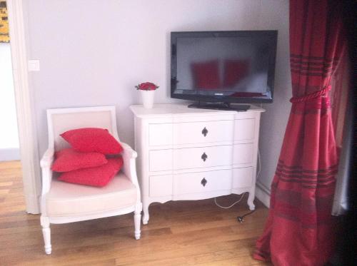 a white dresser with a tv and a chair with red pillows at La Demeure de Laclais in Le Mans