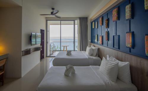 a hotel room with two beds and a balcony at Norn Talay Surin Beach Phuket in Surin Beach