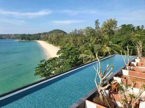 an infinity pool with a view of the ocean and a beach at Norn Talay Surin Beach Phuket in Surin Beach