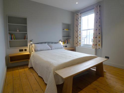 1 dormitorio con 1 cama, suelo de madera y ventana en Kittiwake Cottage, en Scarborough