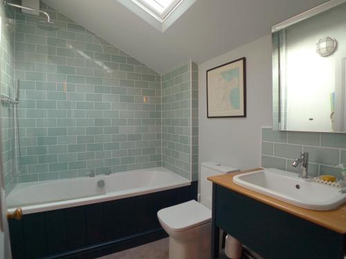 a bathroom with a tub and a toilet and a sink at Kittiwake Cottage in Scarborough