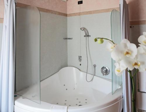 e bagno con vasca, doccia e fiori. di Hotel Contà Taste The Experience a Pieve di Soligo