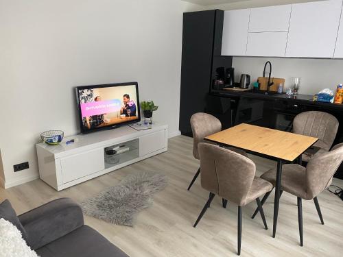 a living room with a television and a table and chairs at Suuremõisa Holiday Apartment with Sauna in Suuremõisa