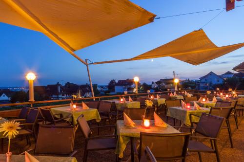 a restaurant with tables and candles on a roof at night at Hotel Restaurant Hansjakob in Hagnau