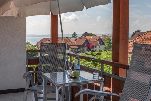 a table and chairs on a balcony with an umbrella at Hotel Restaurant Hansjakob in Hagnau