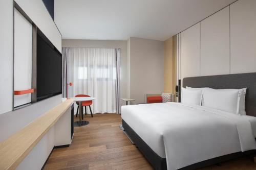 a bedroom with a large white bed and a tv at Holiday Inn Express Beijing Yizhuang Center by IHG in Beijing