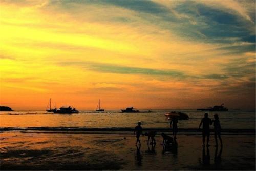 a group of people walking on the beach at sunset at The Deck patong Luxury Apartments The Deck patong in Patong Beach