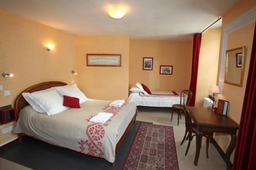 a hotel room with two beds and a desk at Hôtel Les Templiers in Luz-Saint-Sauveur