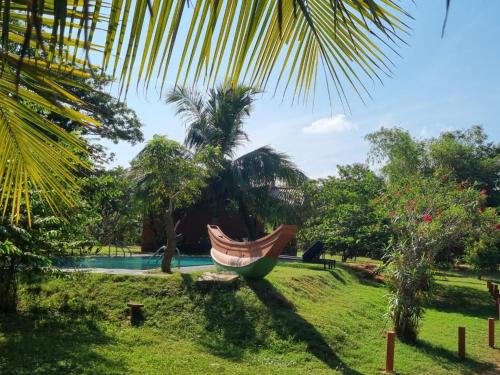 a hammock in a garden next to a pool at Yala Peace Cottages in Tissamaharama