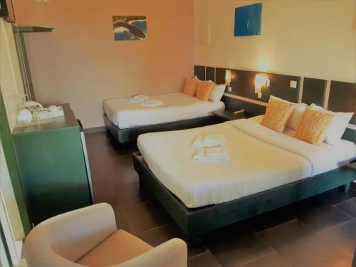 a hotel room with two beds and a chair at Hôtel Les Embruns Du Baril in Basse Vallée