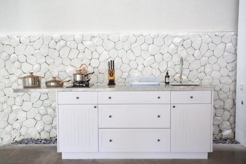 a white counter in a kitchen with a stone wall at Calm Villa in Seminyak