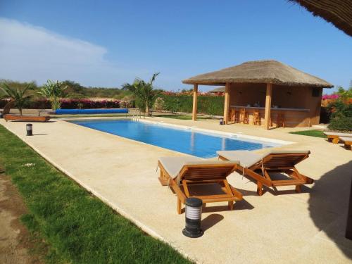 a swimming pool with chairs and a gazebo at Villa Rebecca in Nianing