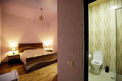 een slaapkamer met een bed en een toilet. bij Nickos Hotel in Koetaisi