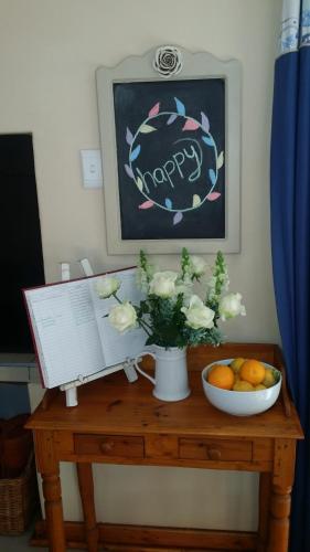 a table with a vase of flowers and a bowl of oranges at 75 on Milner Lodge in Kimberley
