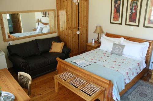 a bedroom with a bed and a couch and a mirror at 75 on Milner Lodge in Kimberley