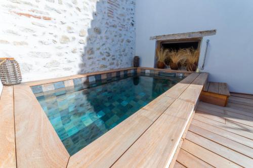 een zwembad met een houten terras en een open haard bij Le S in Argelès-sur-Mer