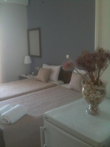a bedroom with two beds and a vase of flowers on a table at Almare (Δίκλινο Δωμάτιο) in Káto Almirí