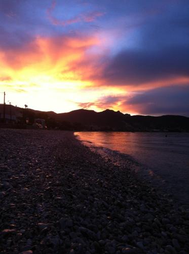 a sunset on a beach with a rocky shore at Almare (Δίκλινο Δωμάτιο) in Káto Almirí