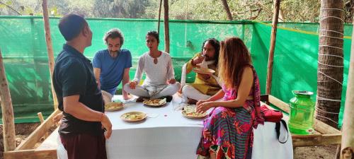 a group of people sitting around a table eating food at TantraLoka Retreat Centre in Arambol