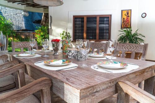 a wooden table with plates and glasses on it at Amani Paradise - Luxury Villas in Diani Beach