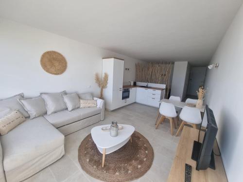 uma sala de estar com um sofá branco e uma mesa em Superbe Studio Rénové les pieds dans l'eau! em Marseillan