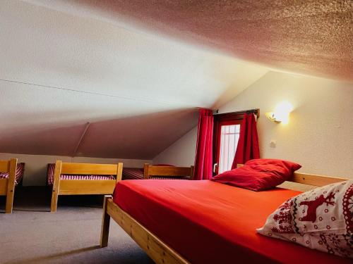 um quarto com uma cama com lençóis vermelhos e uma janela em Les Menuires skis aux pieds em Les Menuires