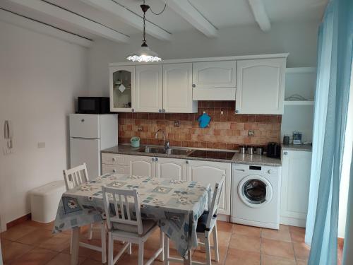 a kitchen with white cabinets and a table with chairs at MOLO 78 Case Vacanze in Cefalù