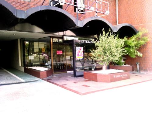 a store front of a building with a tree in front of it at Hotel Sun Plaza Sakai in Sakai
