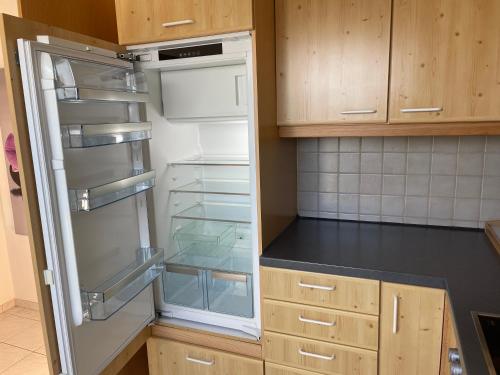 an empty refrigerator in a kitchen with wooden cabinets at Brulaire Büsingen am Hochrhein in Busingen am Hochrhein