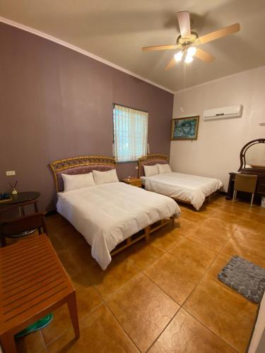a bedroom with two beds and a ceiling fan at 樂觀軒民宿 in Taitung City