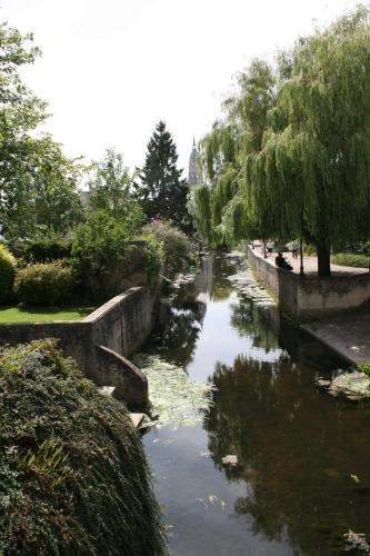 a river in a park with trees and bushes at Gites les Pourquoi Pas - Résidence de Tourisme DSV Bayeux in Bayeux