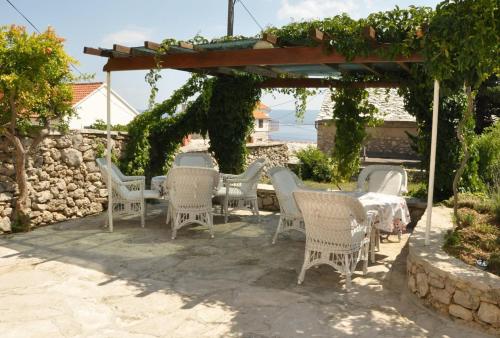 eine Terrasse mit einem Tisch und Stühlen unter einer Pergola in der Unterkunft Apartments Adriana in Bol