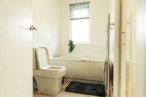 a bathroom with a toilet and a tub and a window at No 4 the Highlands in Strathpeffer