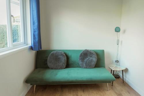 a green couch in a room with a window at No 4 the Highlands in Strathpeffer