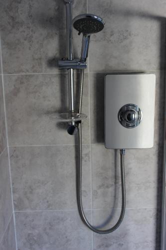 a shower with a shower head in a bathroom at The Hampton Beautiful 3 Bedroom House with Conservatory & Garden in Scarborough