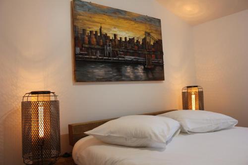 a bed with two lamps and a painting on the wall at Gîte de la Colinière 4 personnes in Le Boupère