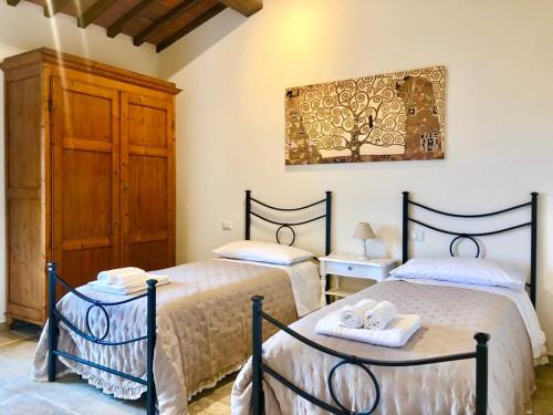 a bedroom with two beds and a painting on the wall at Laura Chianti Vacanze in Poggibonsi