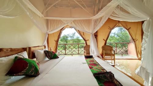 A bed or beds in a room at Murchison Falls Bamboo Village