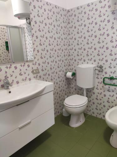 a bathroom with a toilet and a sink and a mirror at Appartamento Il Nespolo in Pomonte