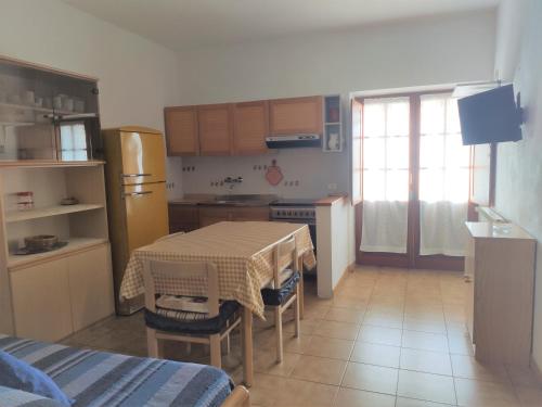 a kitchen with a table and a kitchen with a refrigerator at Appartamento Il Nespolo in Pomonte