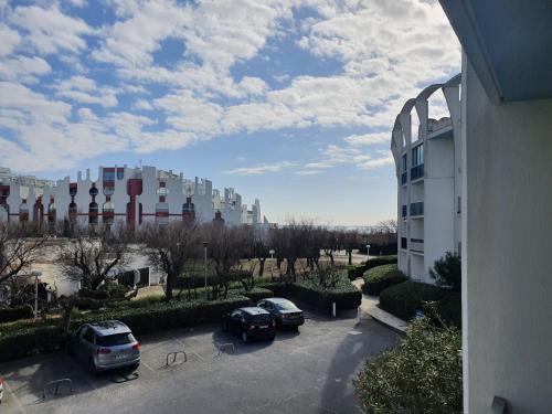 ein Parkplatz mit Autos vor einem Gebäude in der Unterkunft Studio la grande motte, parking, petite vue mer in La Grande-Motte