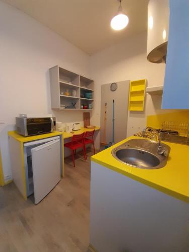 cocina con fregadero y encimera amarilla en Résidence Les Volets Bleus: Studio de 30 m² classé 2 *, en Rochefort