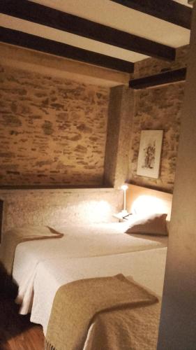 a bedroom with a white bed with a brick wall at Posada Real de Las Misas in Puebla de Sanabria