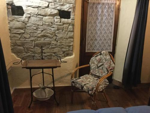 a room with a chair and a table and a stone wall at Orbregno Country Houses with Personal Wine Cellar in Prasco