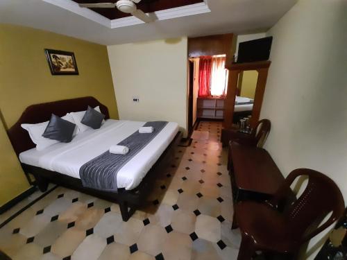 a bedroom with a bed and a chair in it at HOTEL CAVERI COMFORT INN in Madikeri