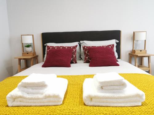 - un lit avec des couvertures blanches et des oreillers rouges dans l'établissement Les Bulles d'Aÿ - Studio, à Ay