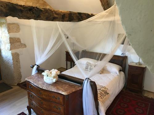 a bedroom with a canopy bed and a wooden dresser at Pérard Chambres D’Hotes in Caylus