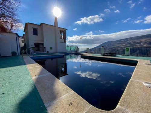 a swimming pool with the sun reflecting in the water at La Higuera in Bubión