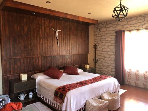 a bedroom with a bed with a cross on the wall at Quinta Hotel los Duraznos in Villa Doctor Mora